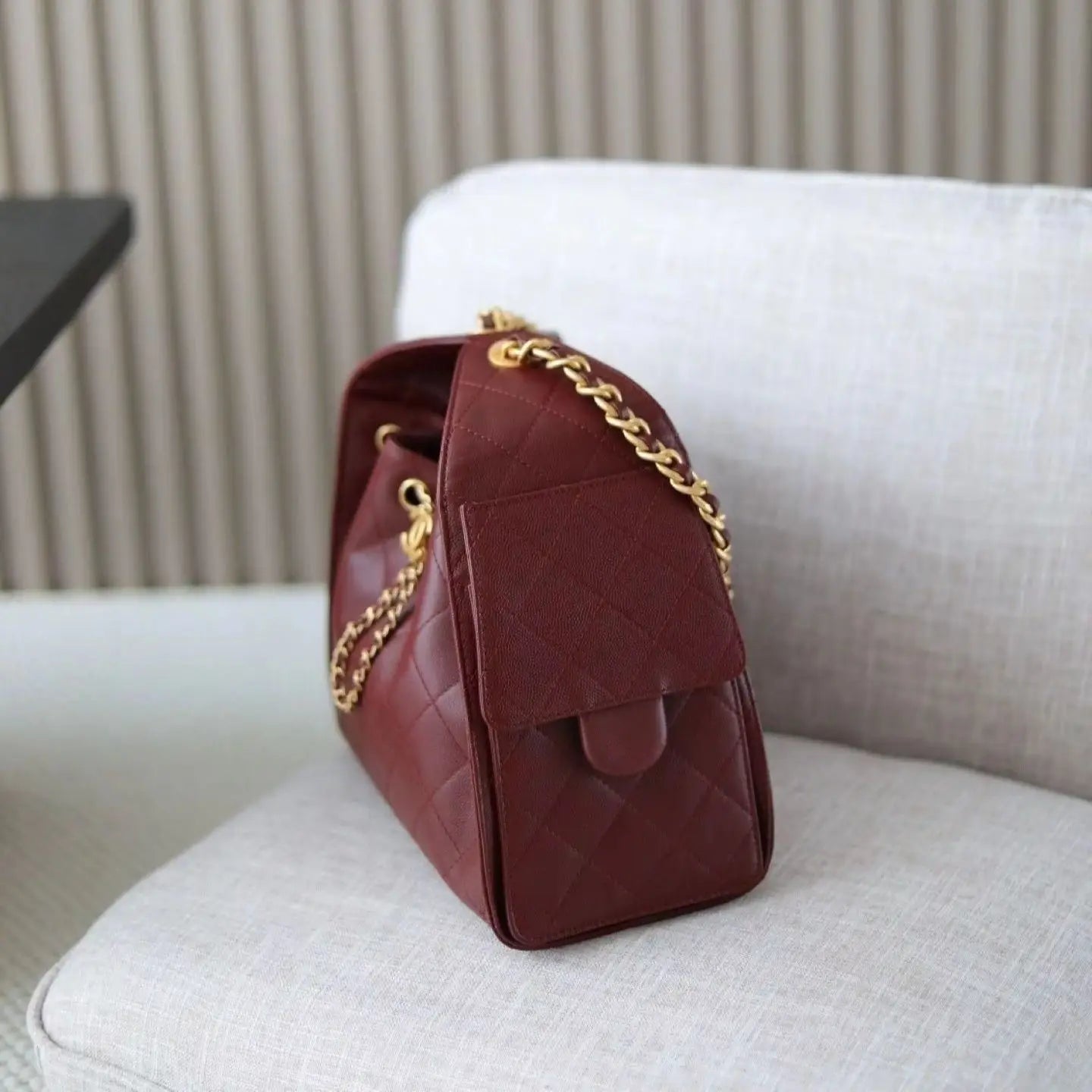 Red rhombus check drawstring bucket bag with a vintage metal chain shoulder strap and layered flap design.