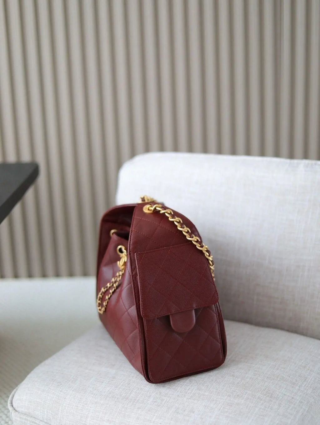 Red rhombus check drawstring bucket bag with a vintage metal chain shoulder strap and layered flap design.
