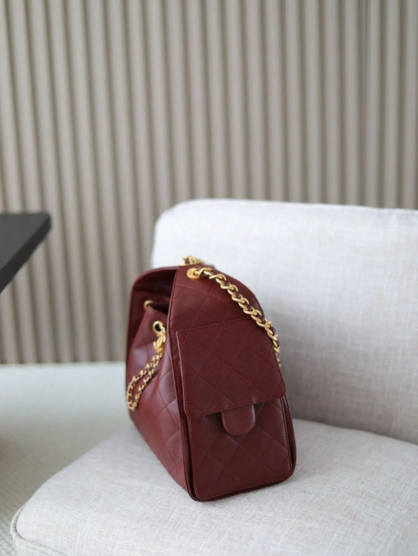 Red rhombus check drawstring bucket bag with a vintage metal chain shoulder strap and layered flap design.